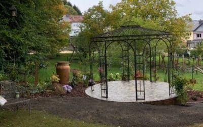 Réalisation d’une terrasse ronde accueillante en pierre naturelle et gloriette élégante en fer forgé